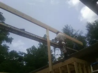 Carpenter setting a ridge beam over a new addition frame — Ice Dam Removal by Roofing Brothers in Frostproof