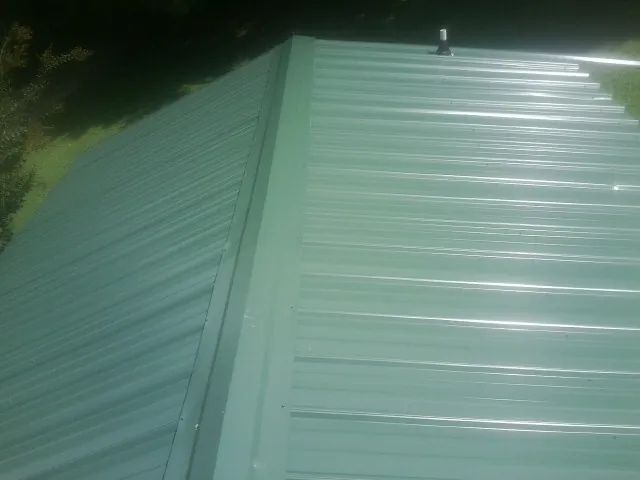 New green metal panels meeting at the ridge of a roof — Flat Roof Repair work by our crew in Frostproof